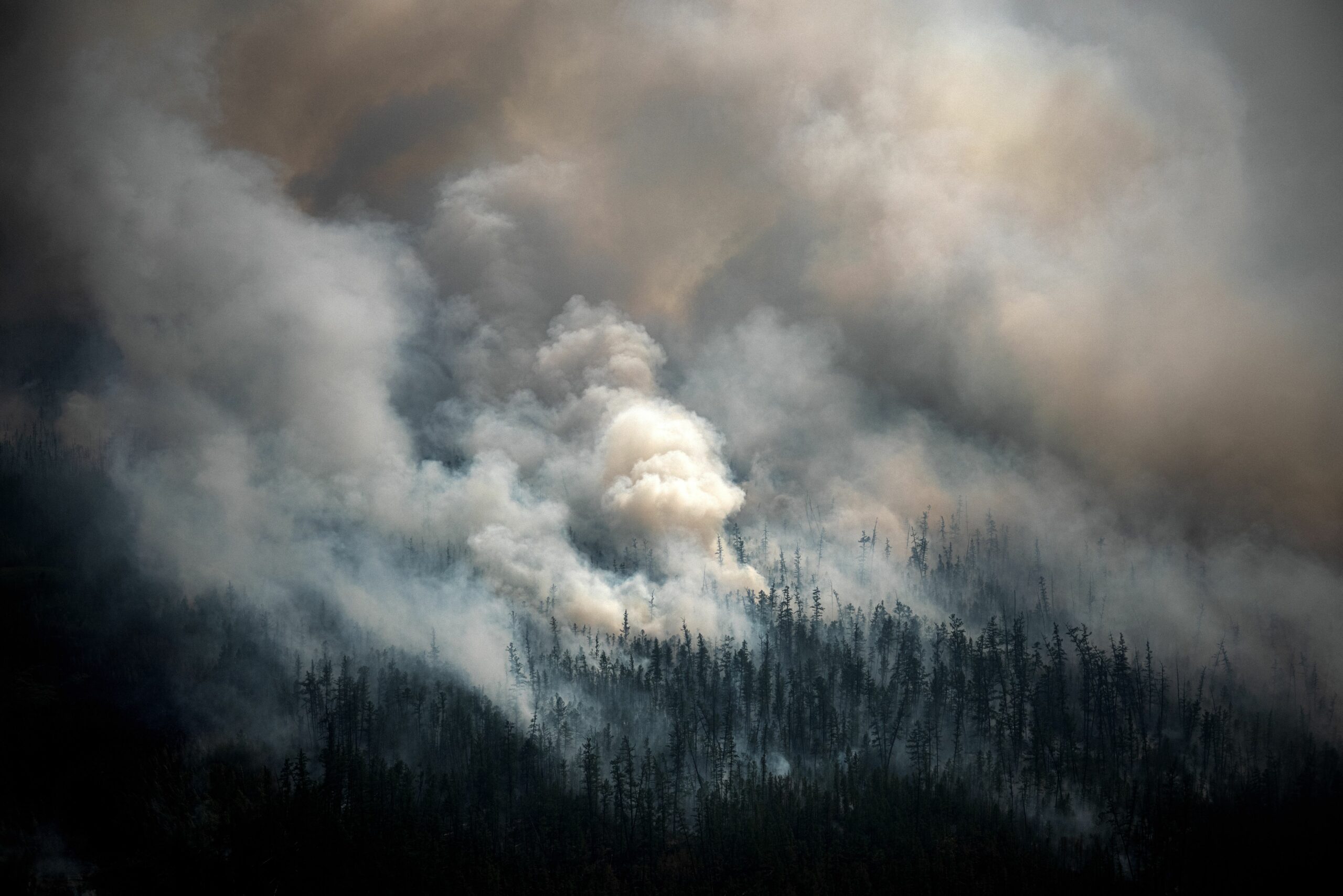 This aerial picture taken from an airplane on July 27, 2021, shows the smoke rising from a forest fire outside the village of Berdigestyakh, in the republic of Sakha, Siberia. Credit: Dimitar Dilkoff/AFP via Getty Images