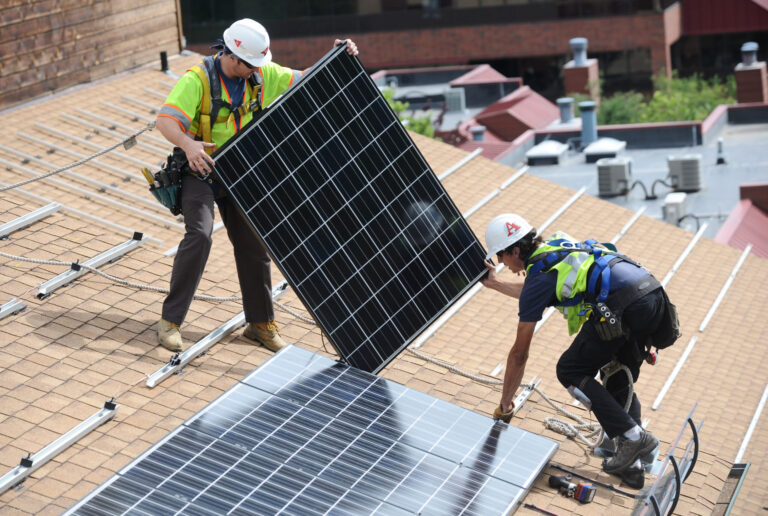 Workers install solar panels on the roof of an apartment complex in Colorado. Credit: Marty Caivano/Digital First Media/Boulder Daily Camera via Getty Images