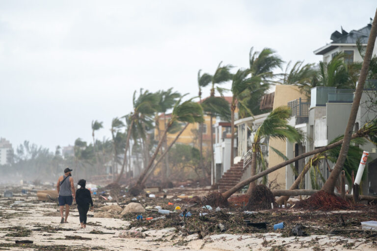 People walk along the beach looking at property damaged by Hurricane Ian on Sept. 29, 2022 in Bonita Springs, Florida. Credit: Sean Rayford/Getty Images