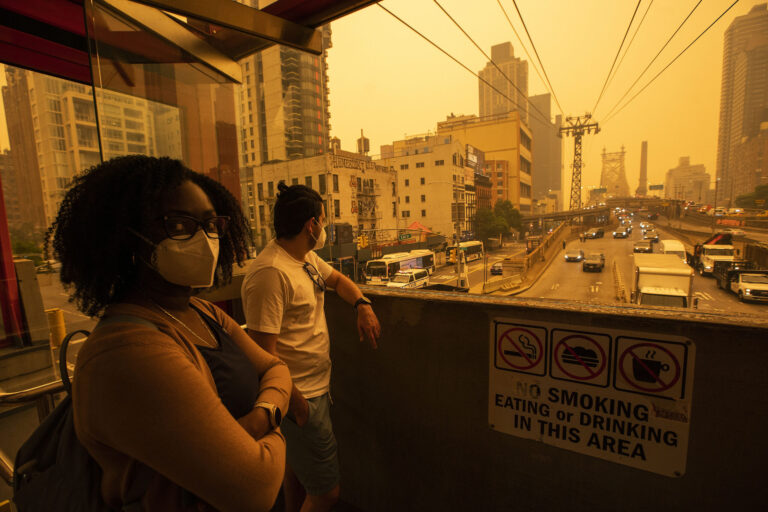 People wear masks as they wait for the tramway to Roosevelt Island as smoke from Canadian wildfires casts a haze over the area on June 7, 2023 in New York City. Credit: Eduardo Munoz Alvarez/Getty Images