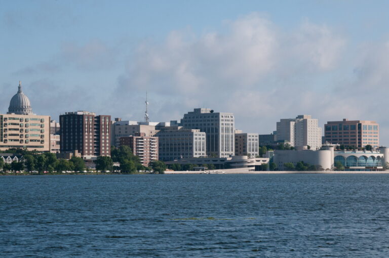 The Wisconsin state capitol rises behind lakeside buildings in Madison, Wisconsin, where the Latino Academy of Workforce Development, a nonprofit aimed at building community through adult education, sponsored a community air monitoring program this summer. Credit: Education Images/Universal Images Group via Getty Images.