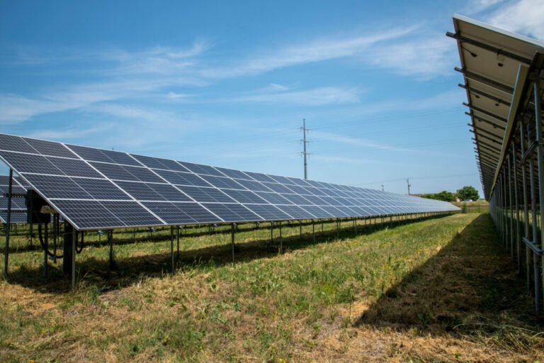 A high tension electrical power pole is seen in the background of a solar array in Blaine, Minn. Credit: Michael Siluk/UCG/Universal Images Group via Getty Images