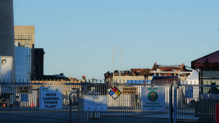 Remnants of the a massive battery fire that took place a year ago lie behind a guarded gate at Moss Landing Powder Plant. Credit: Claire Barber/Inside Climate News