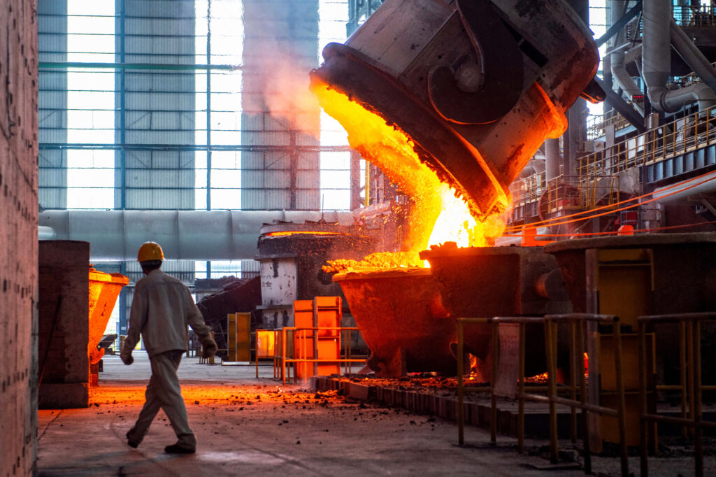 A worker walks past molten steel at a factory in Huai