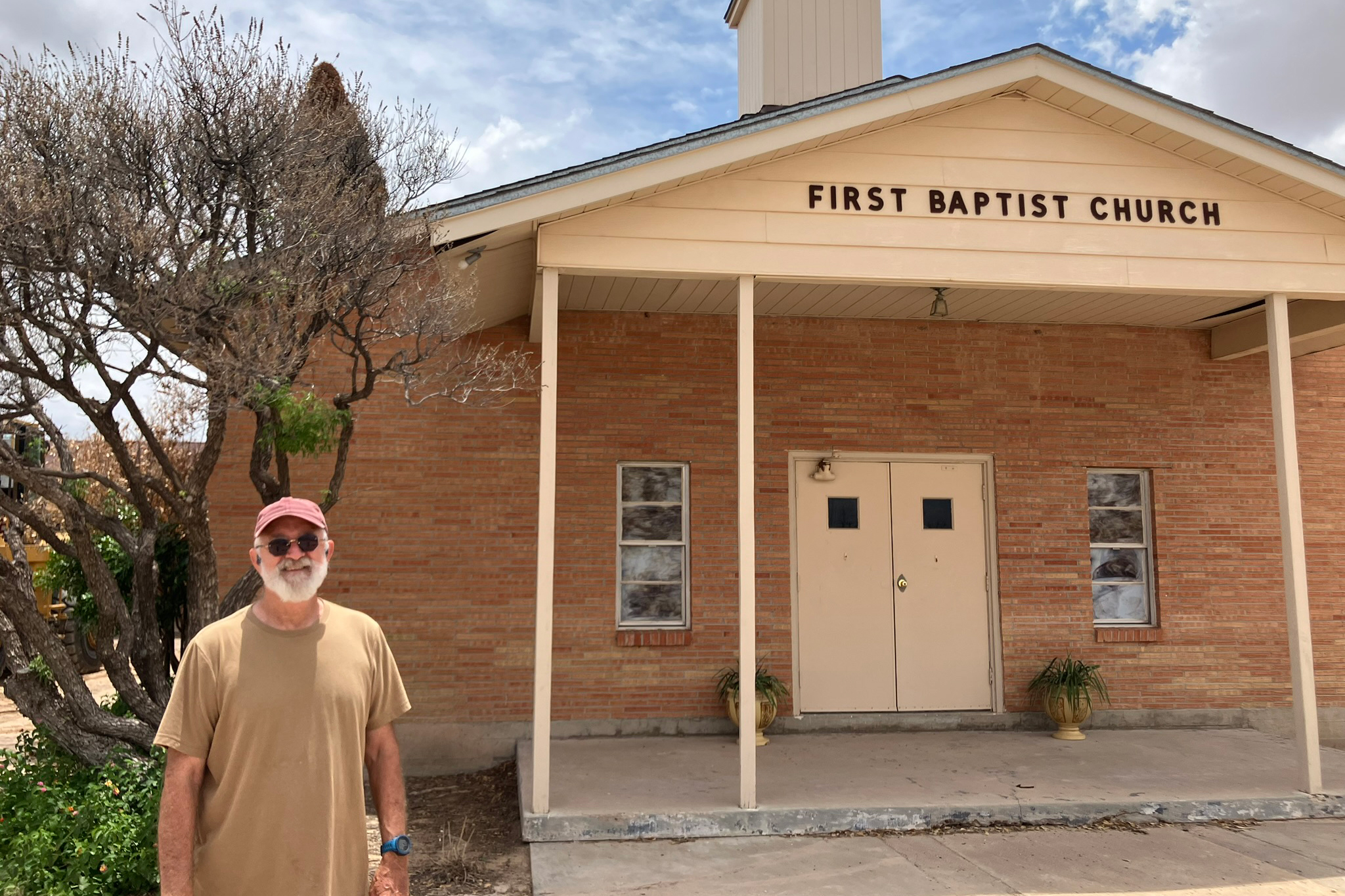 Le pasteur David Tucker se tient devant la première église baptiste de Grandfalls. Tucker est devenu pasteur de l'église l'été dernier, en plus de son travail à temps plein dans l'industrie pétrolière et gazière. Crédit : Martha Pskowski/Pacte Climat
